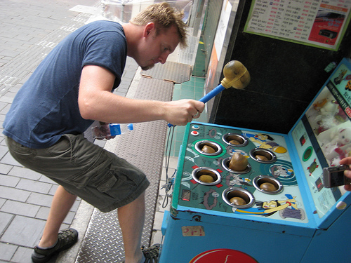 an image of a man playing the wack-a-mole arcade game 